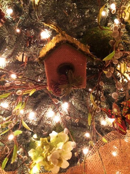 A bird house is hanging from a christmas tree