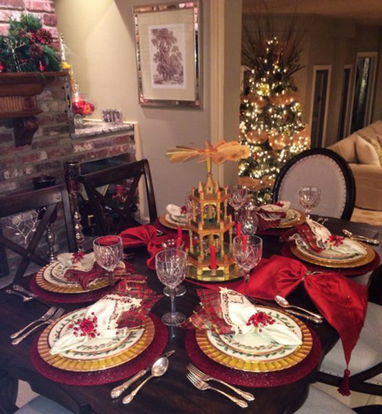 A table set for a christmas dinner with a christmas tree in the background
