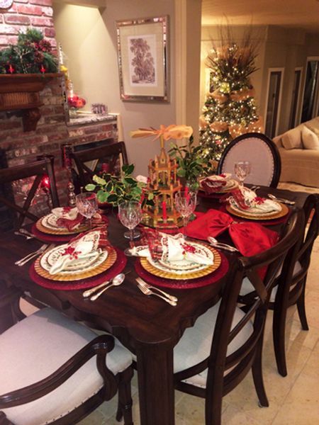 A dining room table set for christmas with a christmas tree in the background
