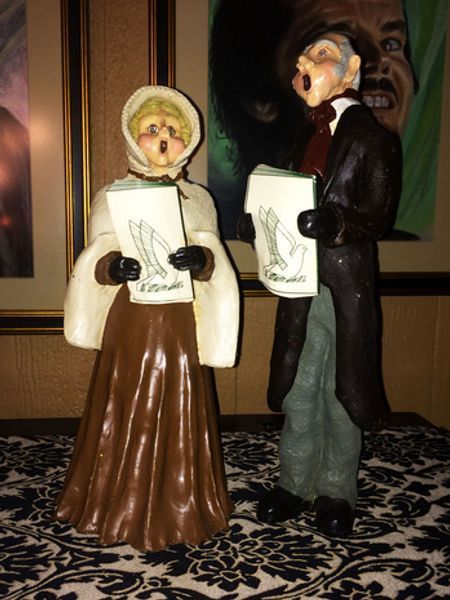 A man and a woman singing christmas carols on a table