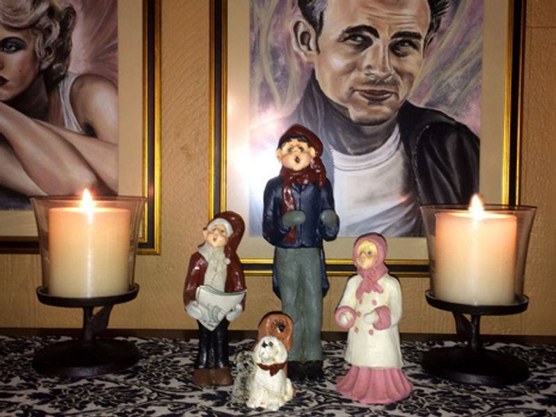 A group of figurines are sitting on a table in front of a painting of dean martin