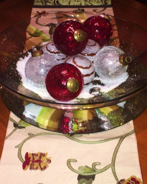 A glass bowl filled with christmas ornaments on a table