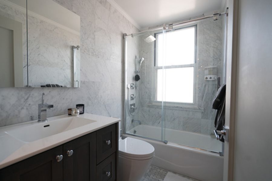 A bathroom with a toilet, sink, shower and window