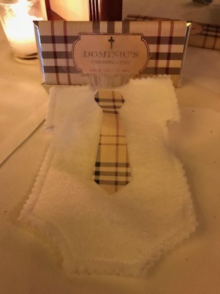 A baby onesie with a plaid tie sits on a table