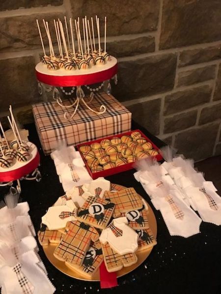A table with a bunch of cookies and cake pops with the letter d on them