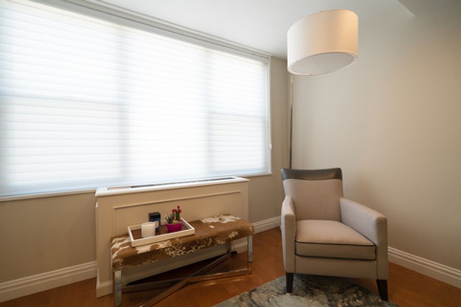 A living room with a chair, bench, lamp and window
