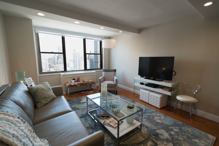 A living room with a couch, coffee table, chair and television