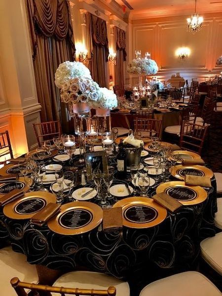 A table set for a wedding reception with black and gold plates
