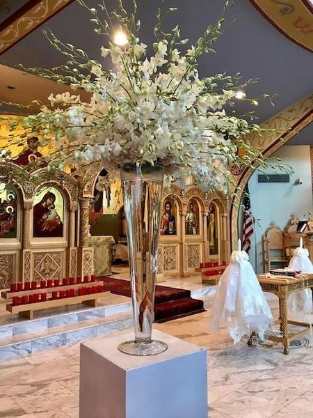 A large vase filled with white flowers is in a church