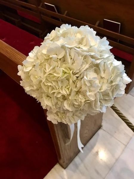 A bouquet of white flowers is sitting on a church bench