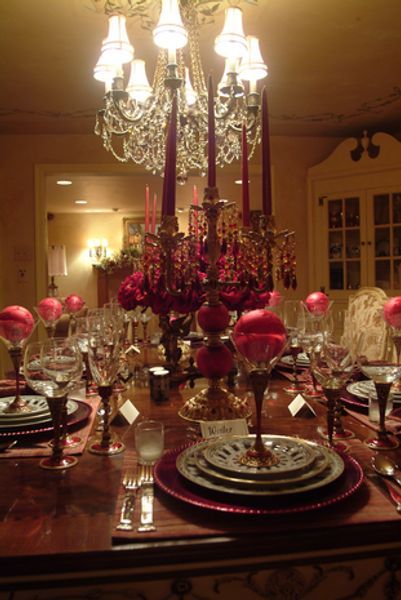 A dining room table with plates candles and a chandelier