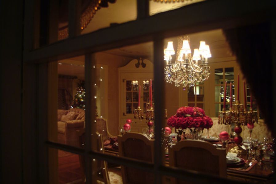 A dining room is decorated for christmas with a chandelier hanging from the ceiling