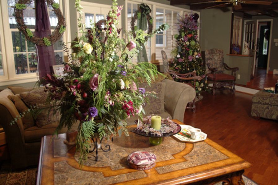 A living room with a christmas tree and a vase of flowers on a table
