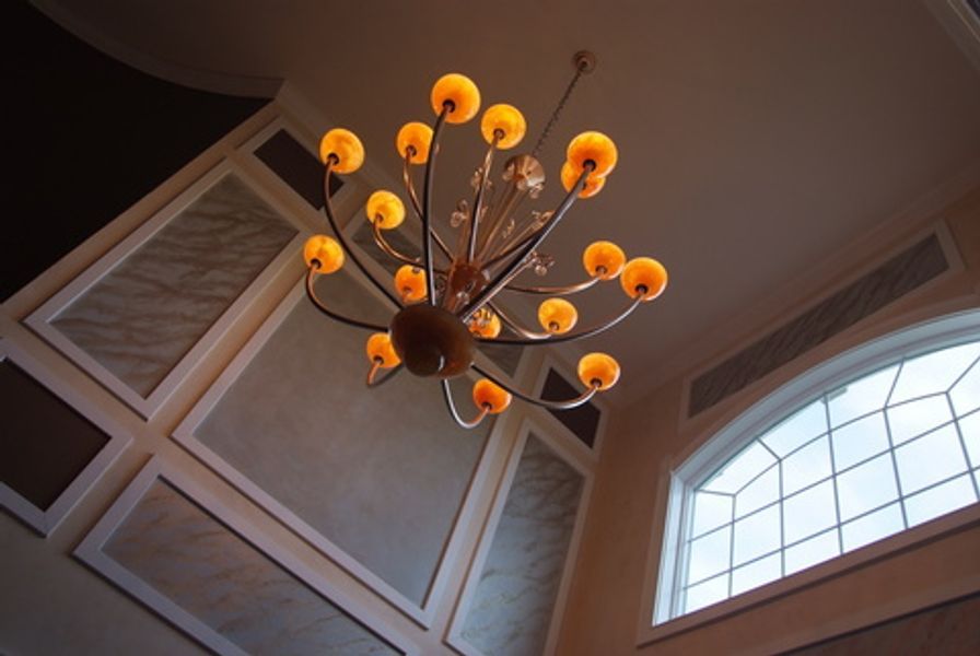 A chandelier is hanging from the ceiling in front of a window