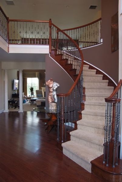 A curved staircase in a house with a statue on the railing