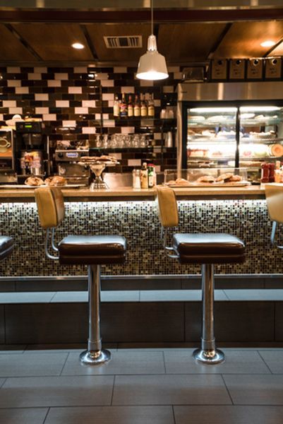 Two bar stools are sitting in front of a bar in a restaurant