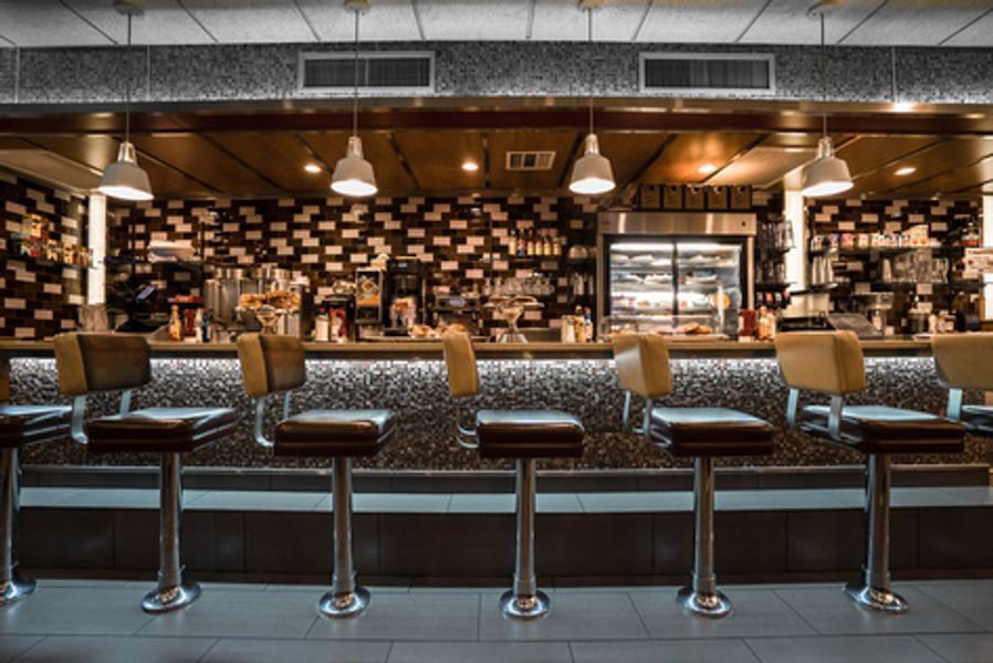 A restaurant with a long bar and stools in front of it