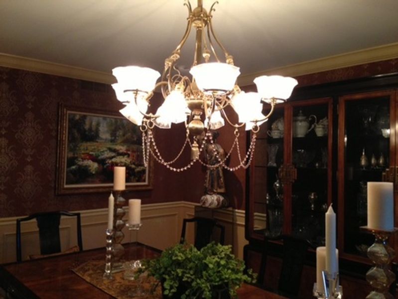 A dining room with a chandelier and candles on the table