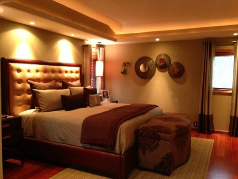 A bedroom with a large bed and two ottomans