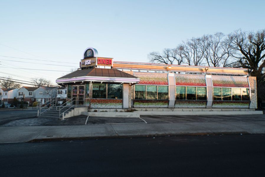 A diner with a lot of windows is sitting on the side of the road