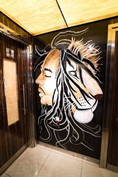 An elevator with a painting of bob marley and a lion on the wall