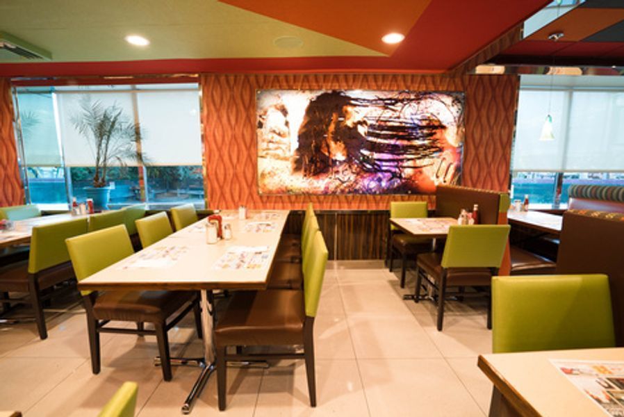 A restaurant with tables and chairs and a large painting on the wall