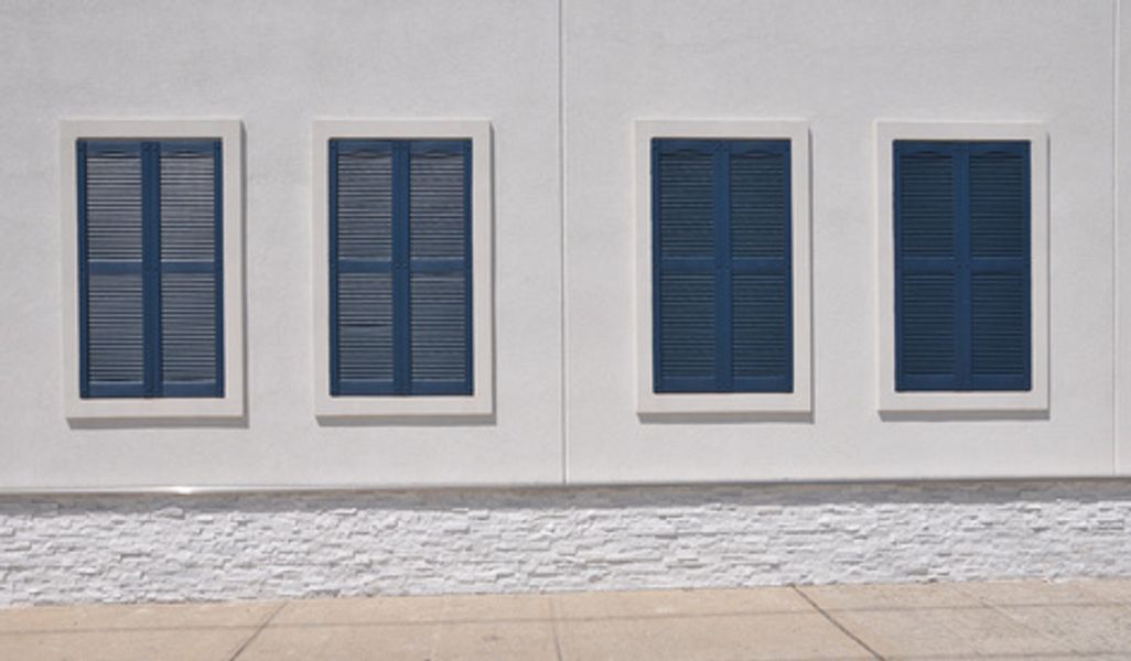 A white building with blue shutters on the windows
