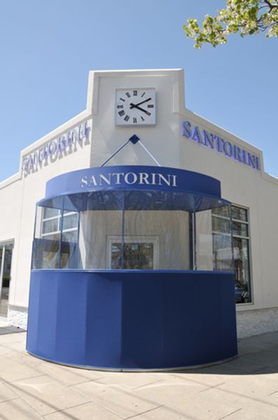 A white building with a blue awning that says santorini
