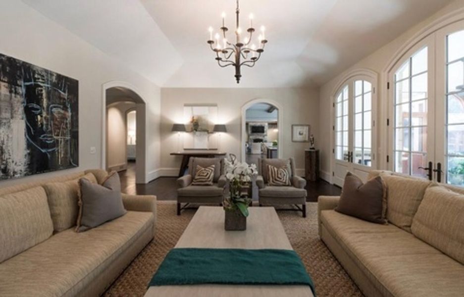 A living room with two couches, two chairs, a coffee table and a chandelier