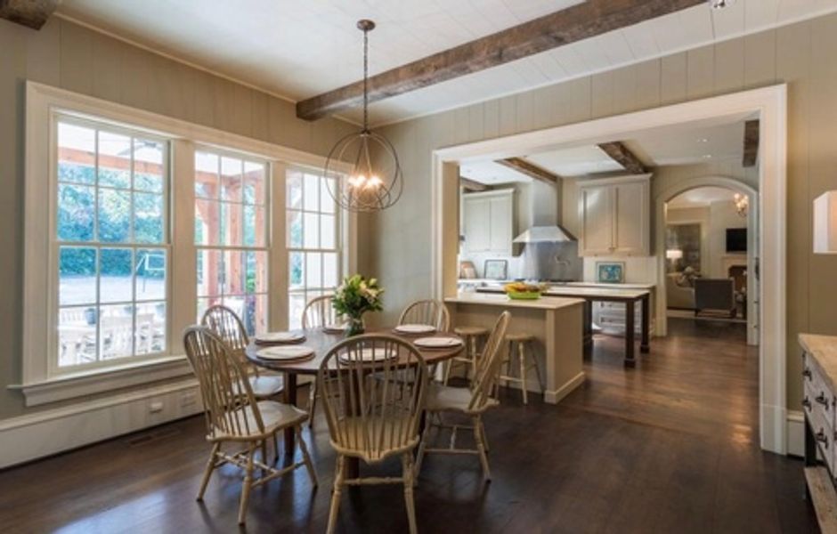 A dining room with a table and chairs and a kitchen in the background