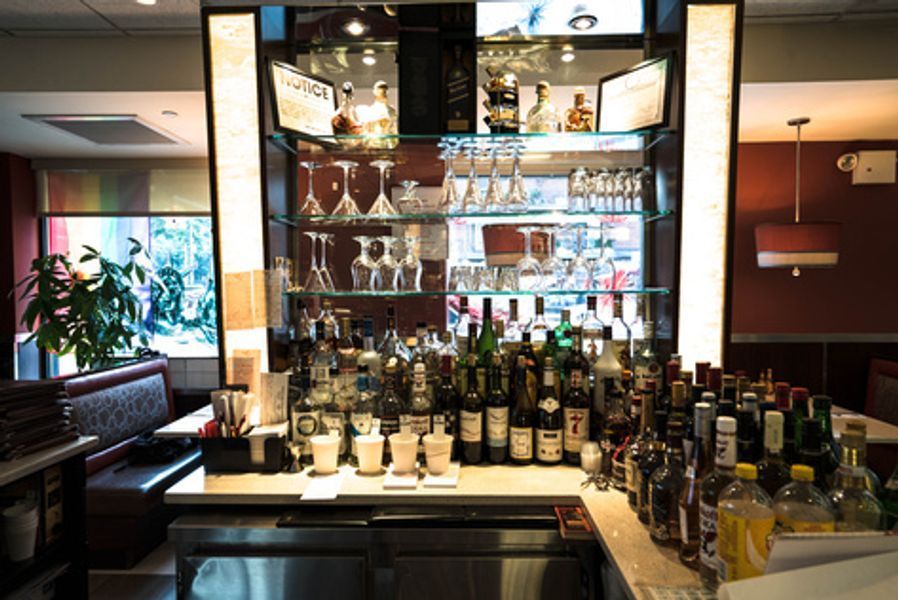 A bar in a restaurant filled with bottles and glasses