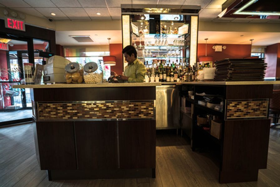 A man is standing behind a bar in a restaurant