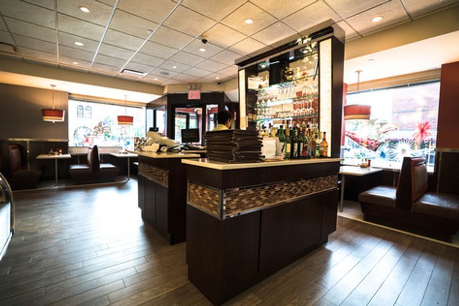 The inside of a restaurant with a bar and tables