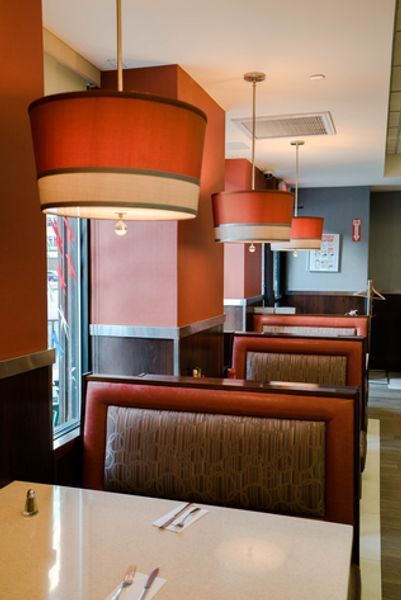 A row of booths in a restaurant with red lamps hanging from the ceiling
