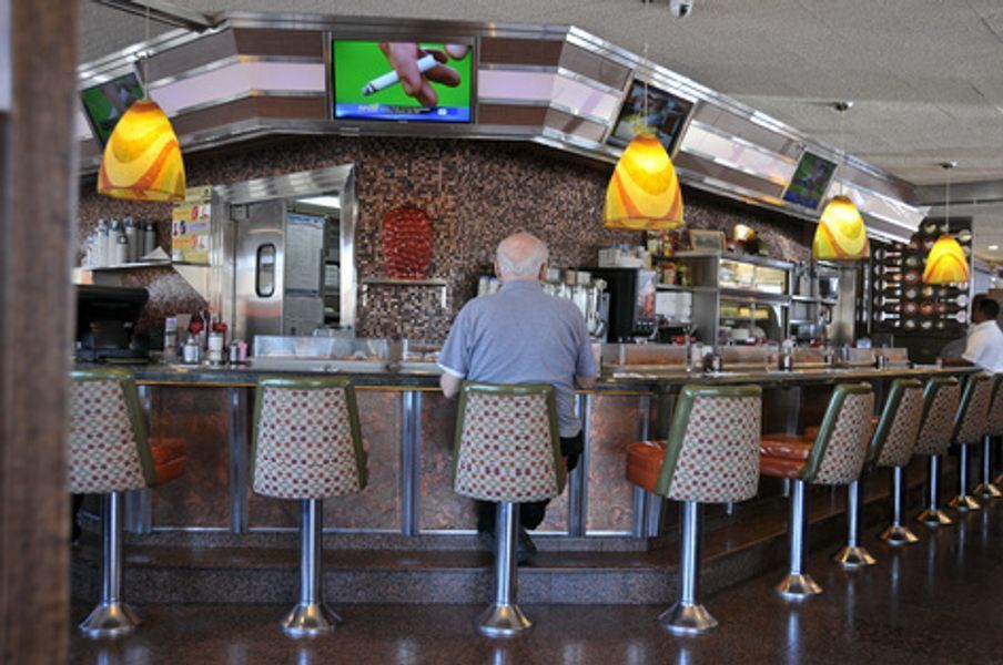 A man is sitting at a counter in a diner