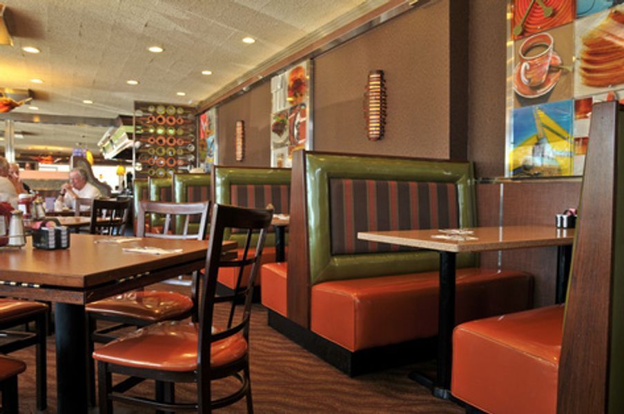 A restaurant with tables and chairs and a painting on the wall