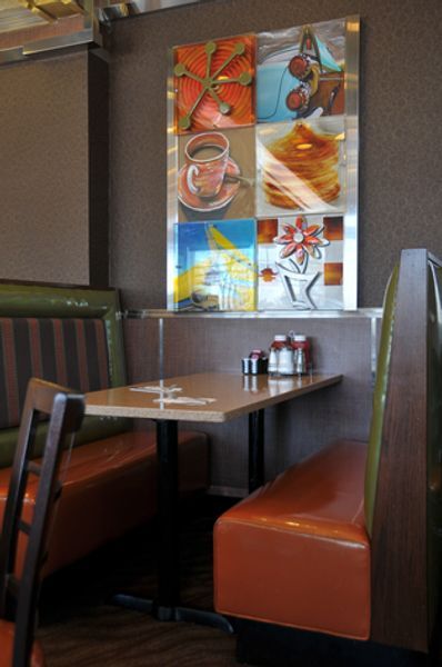 A diner with a painting on the wall above the table