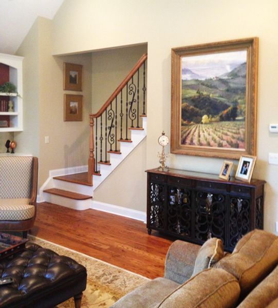 A living room with stairs and a painting on the wall