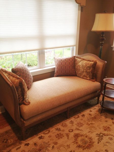 A chaise lounge in a living room next to a window