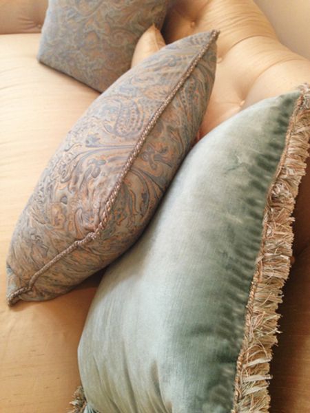 Two pillows are sitting on a couch with fringe