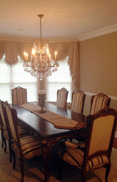 A dining room table and chairs with a chandelier hanging from the ceiling