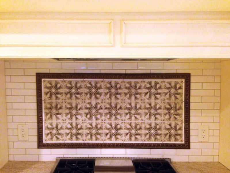 A kitchen with a stove top oven and a tiled wall above it