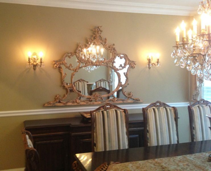 A dining room with a large mirror and a chandelier