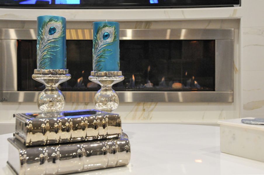 Two peacock feather candles are sitting on top of a stack of books in front of a fireplace