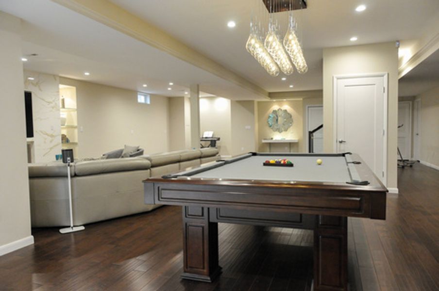 A pool table in a living room next to a couch