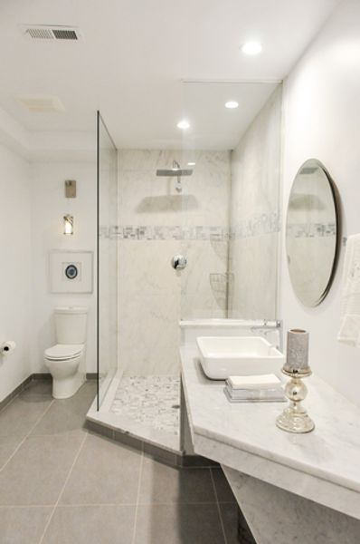 A bathroom with a toilet, sink, mirror and walk in shower