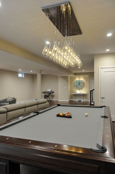 A pool table in a living room with a chandelier hanging from the ceiling