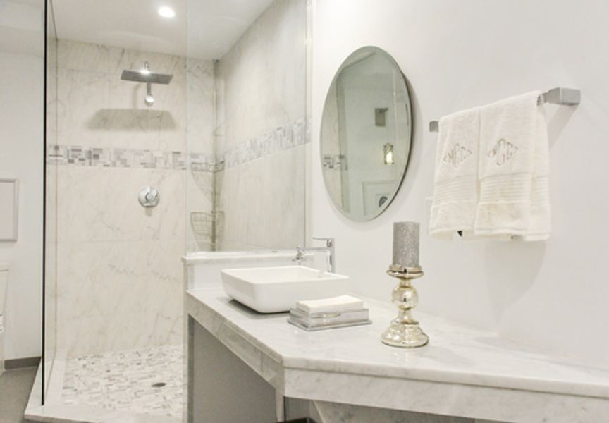 A bathroom with a sink, mirror and shower