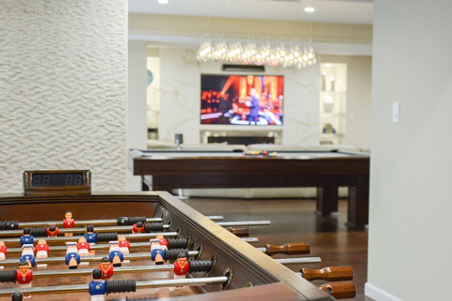 A game room with two pool tables and a foosball table