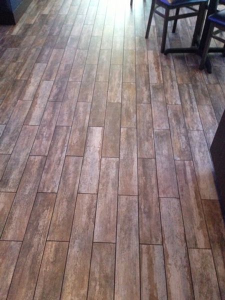 A wooden floor with a table and chairs in the background